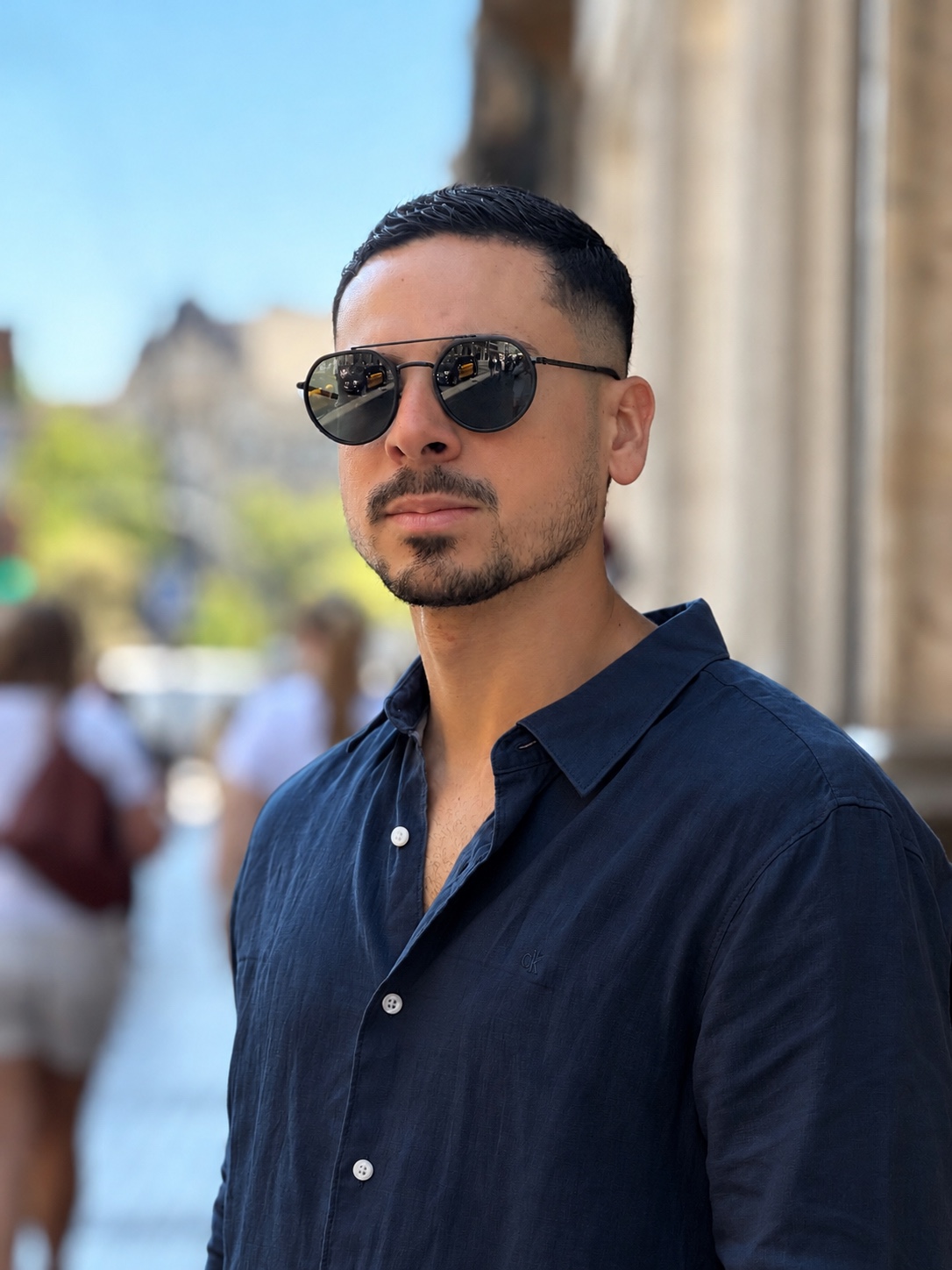 Joel Figueroa con camisa azul marino y gafas de sol en un entorno urbano